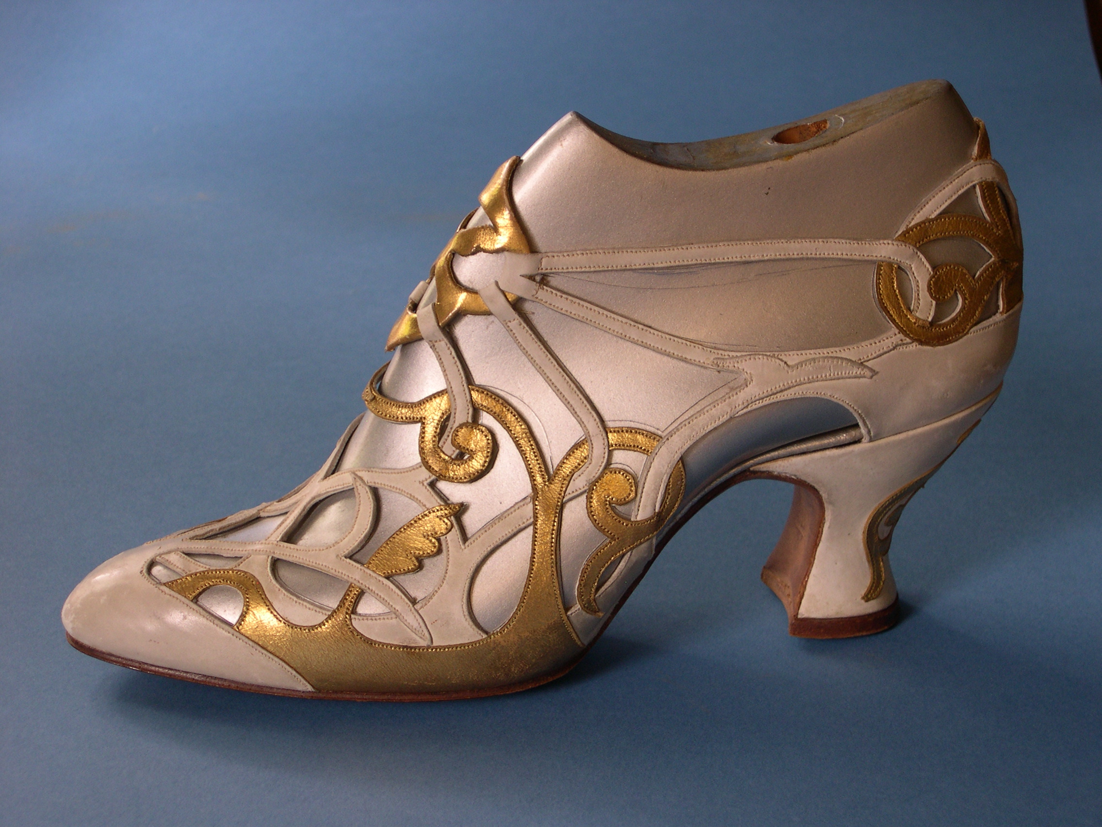 Lady’s shoe, c. 1926-1930 by Claude Robert Wilkinson for Howlett & White Ltd, Norwich. White calf and kid leather, overlaid with gold leaf. 