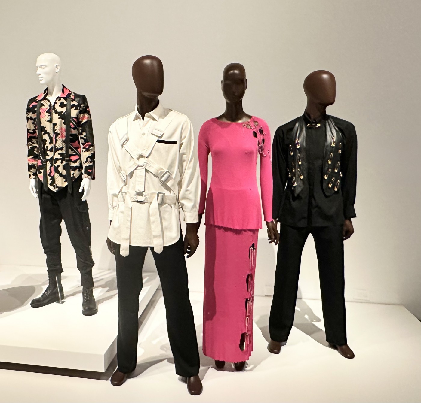 Boy of London Camouflage print punk jacket, circa 1978. United Kingdon / Vivienne Westwood, white cotton straight jacket shirt with rubber buckles, circa 1978, United Kingdom / Zandra Rhodes, punk-inspired ensemble, 1978, United Kingdom / Versace Black Safety pin embellished vest & Shirt 1994 Italy ©Jane Francis