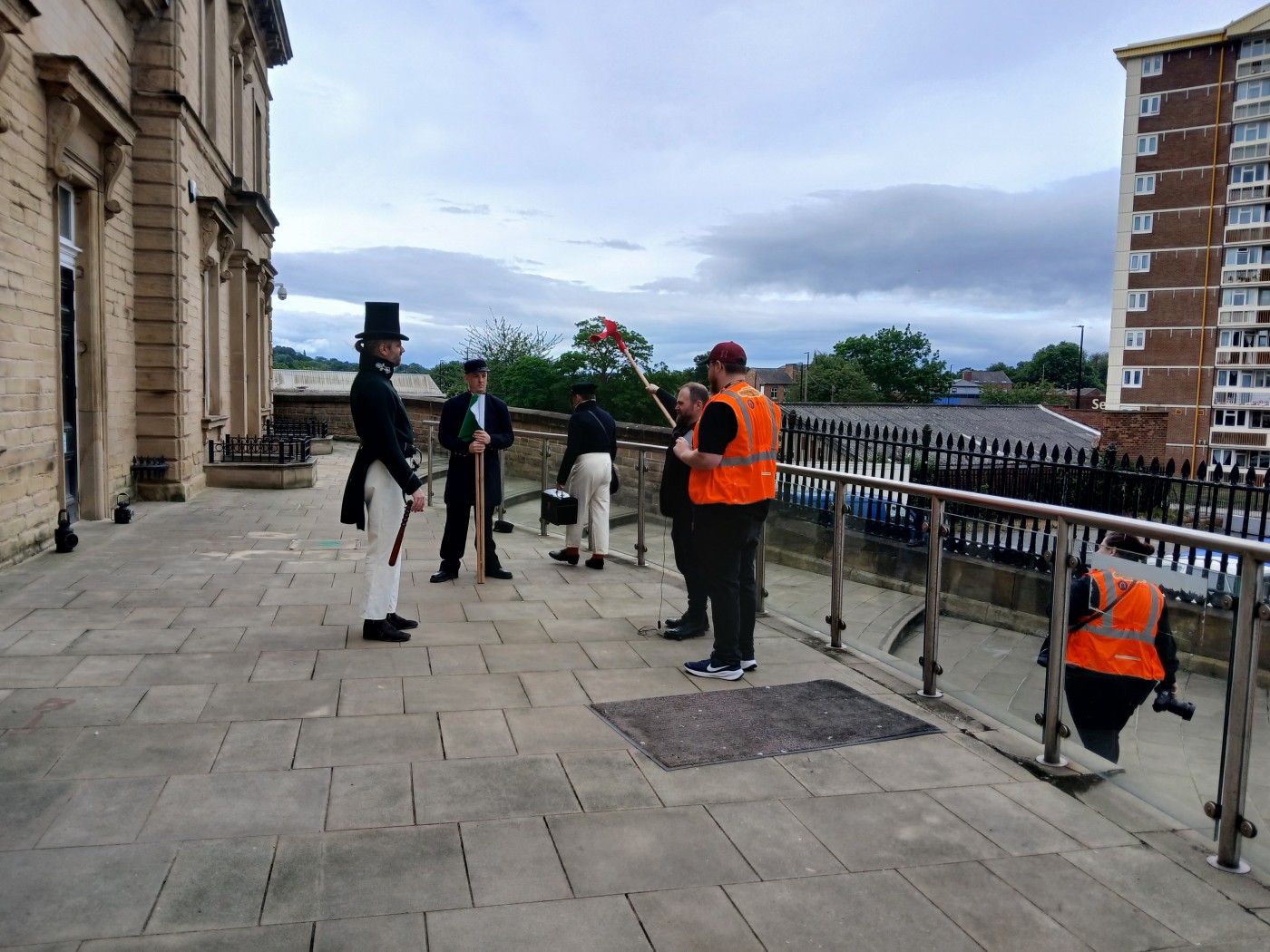 ‘Hurry up and Wait’ models and photographers gathering at Wakefield Kirkgate, while Anthony instructs the 1840s Railway Constable how to signal with his flags. Image courtesy of Dan Nash.