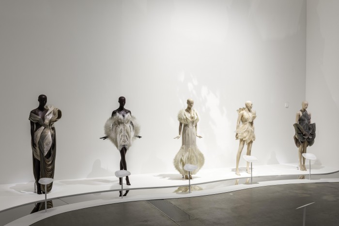 Installation view of ‘Iris van Herpen: Sculpting the Senses’ including (l-r) Genesis dress, from the ‘Meta Morphism’ collection 2022 by Iris van Herpen; Empyrean dress, Empyrean gown and Magnetosphere dress, from the ‘Earthrise’ collection 2021 by Iris van Herpen with collaborators Rogan Brown and Parley for the Oceans; Hypnagogia dress, from the ‘Lucid’ collection 2016 by Iris van Herpen / © Iris van Herpen / Photograph: N Umek © QAGOMA