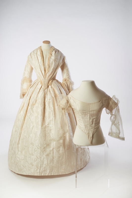 M.2015.048 – 1855 – 1858 wedding gown of figured silk damask shown with matching evening bodice. © The Olive Matthews Collection, Chertsey Museum. Photo by John Chase Photography