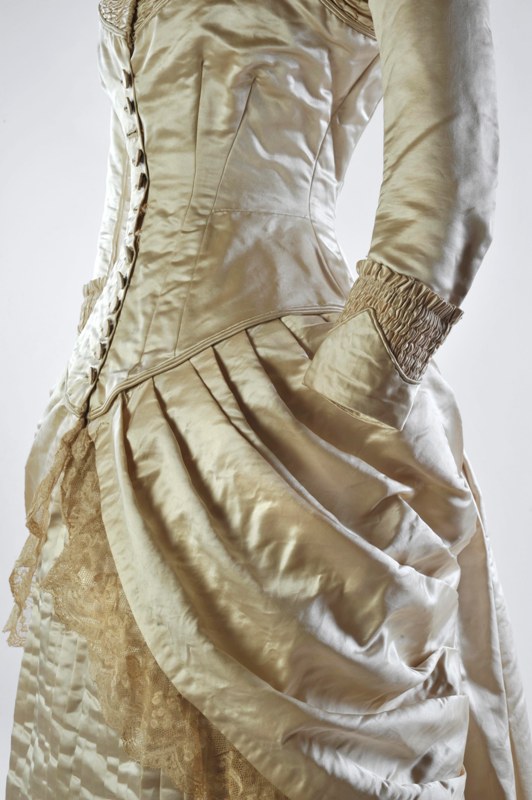 Detail of M.1986.18 – Wedding gown of ivory silk satin, c.1880 – 1885. © The Olive Matthews Collection, Chertsey Museum. Photo by John Chase Photography
