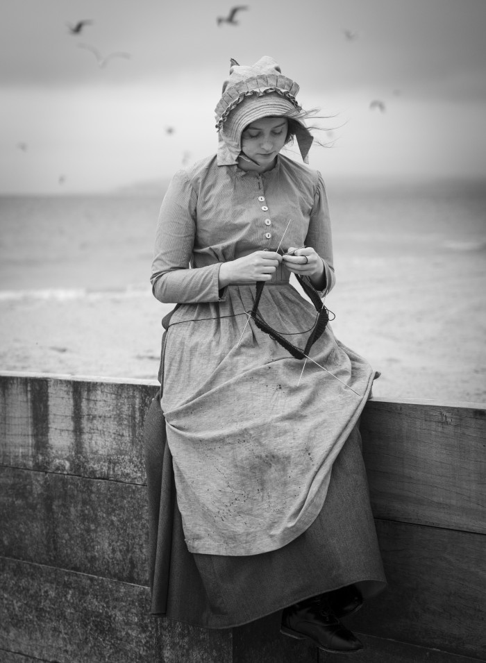 Black and white photograph of a young woman in late nineteenth century working woman’s dress. The outfit was modelled by fellow historical costume student Sophie Bowyer and photographed by Kheyal Roy-Meighoo. Clothing design, making, styling and photo editing by Eleanor Hadfield.